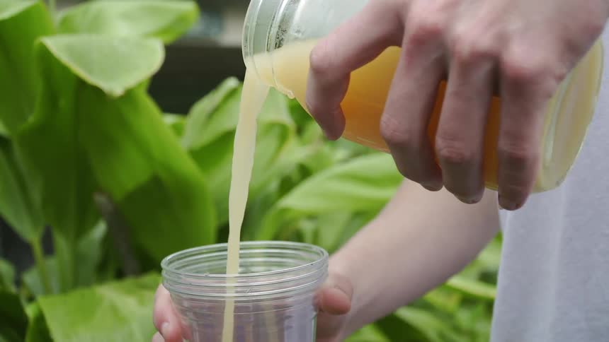 Person pours liquid from a pitcher into a cup
