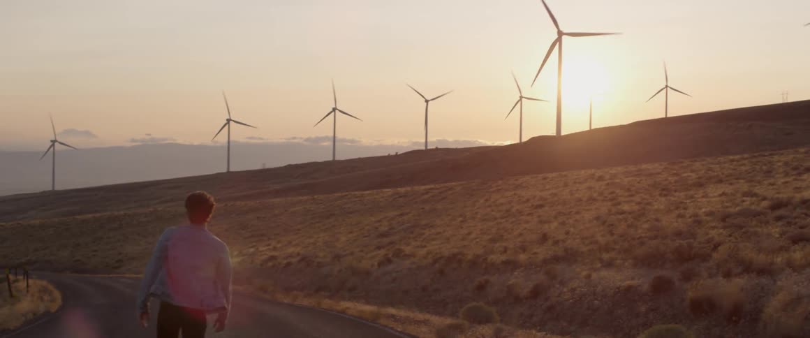 Man walks on a road near the wind turbines