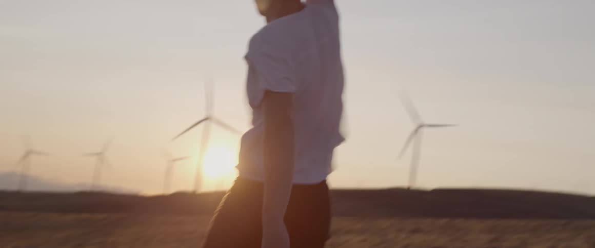 Man waves his jacket around on a windy day near windmills