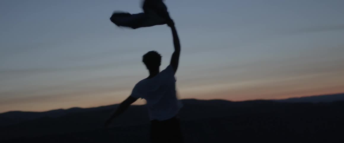 A man holds his jacket up while he walks into the wind