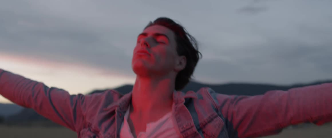 A man stretches out his arms and leans his head back in the wind