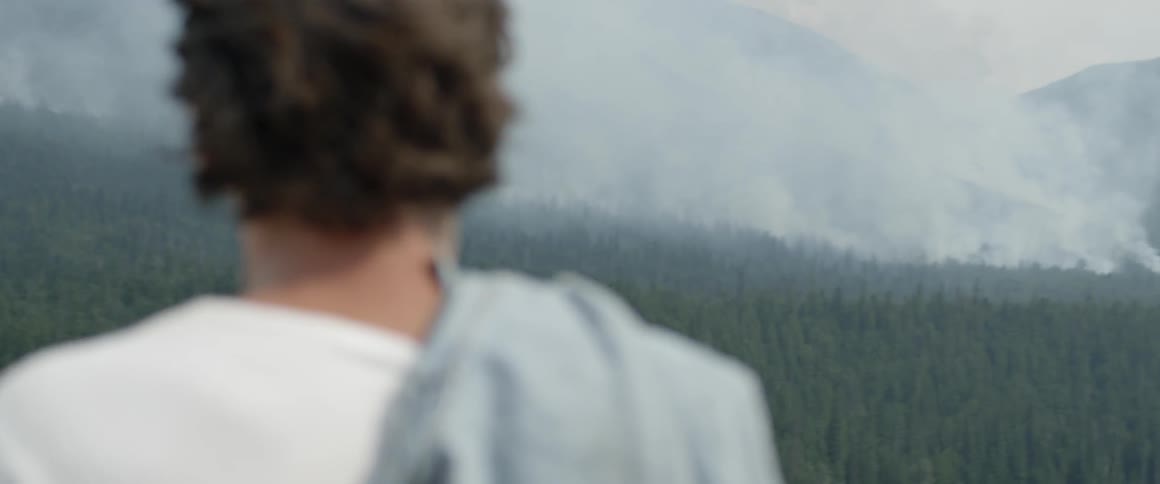 Person stands outside on a hilltop looking out at nature