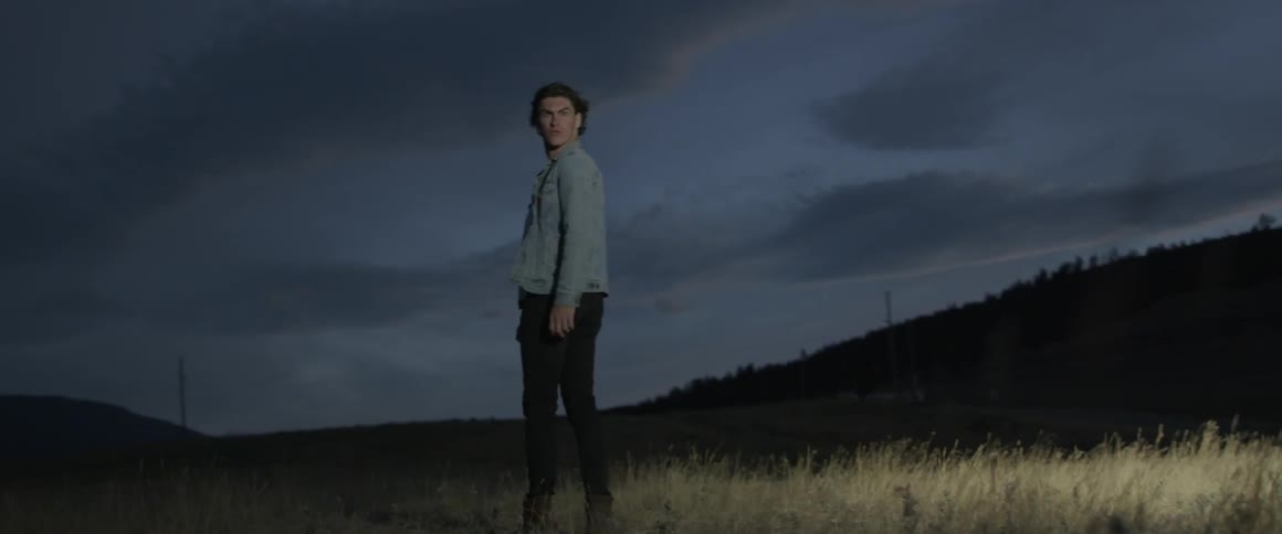 Lights reveal a man standing on the field at dawn