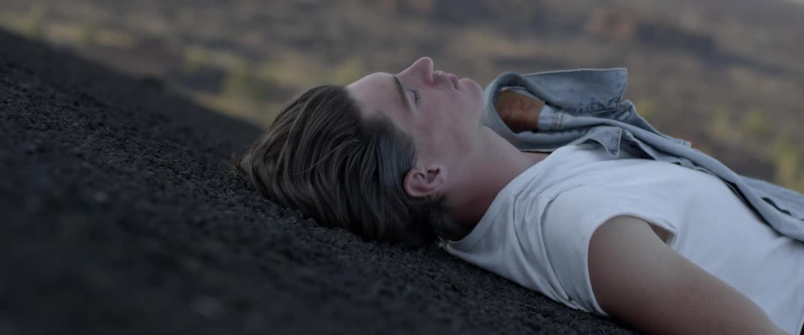 Man lays outside on the ground in the evening