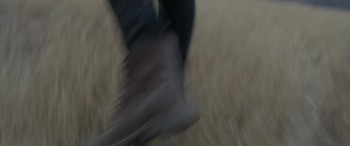 A man wearing boots walks through a field