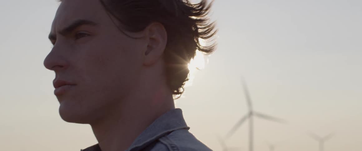 Man is standing outside near wind turbines on sunny day