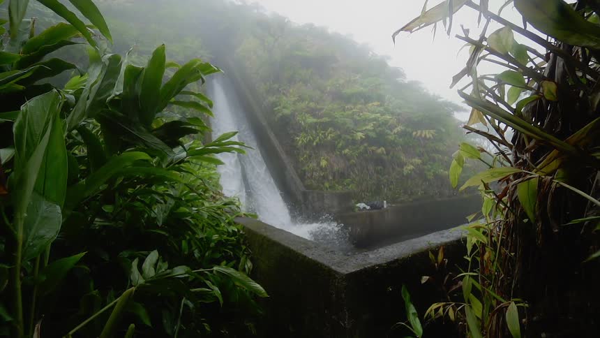 The tall waterfall is covered with fog