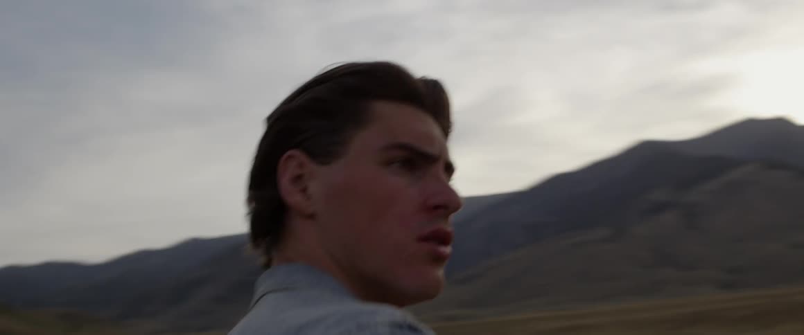 Man walks outside near mountains and looks around