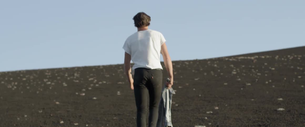 A man carries his jacket up the hill