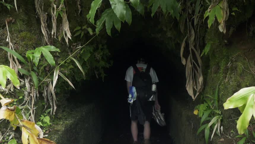 Man walks towards the entrance to a cave