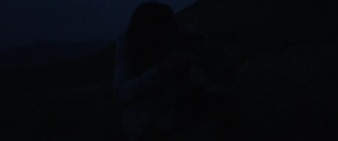 A man holds a rifle in the dark