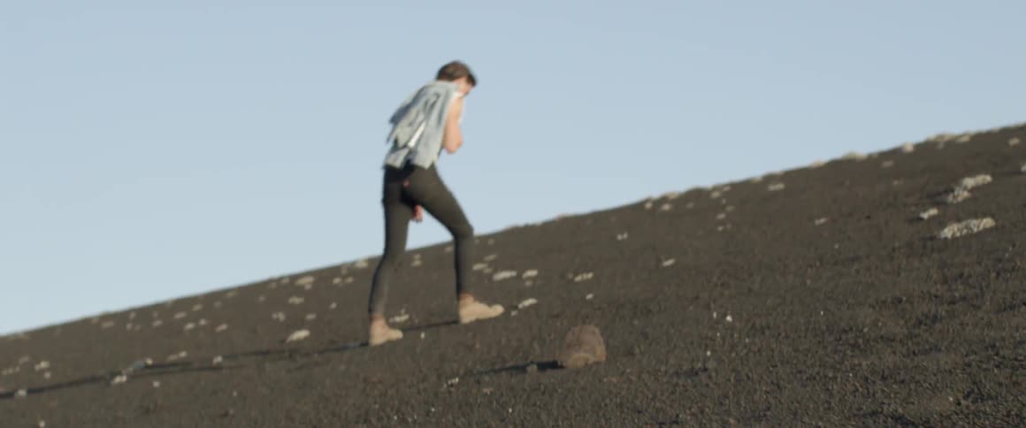 Man walks up a hill under a blue sky