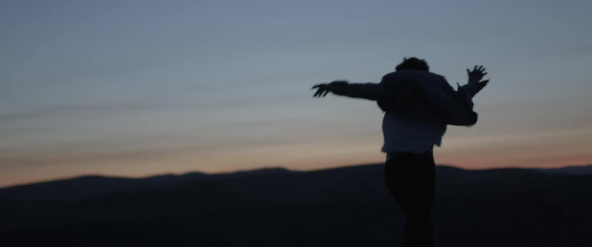 A man holds his arms up as his jacket flaps in the wind