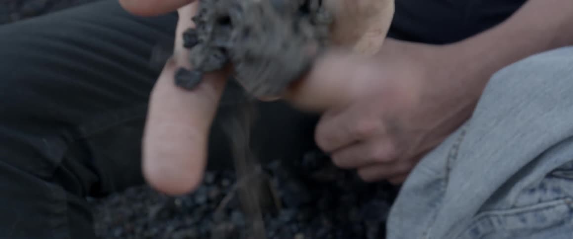 A man crumbles a rock in his hand