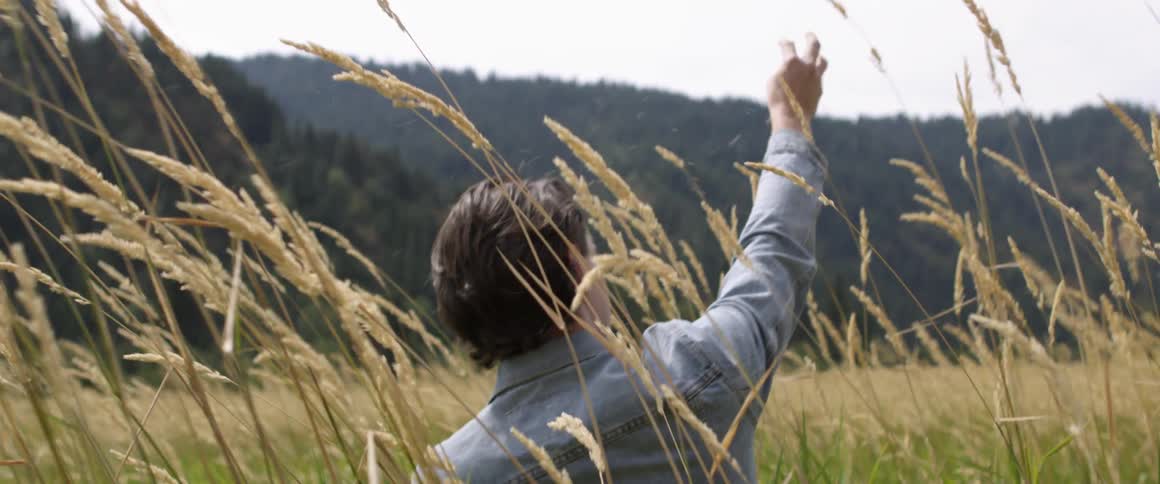 Man wearing a denim jacket sits in a field