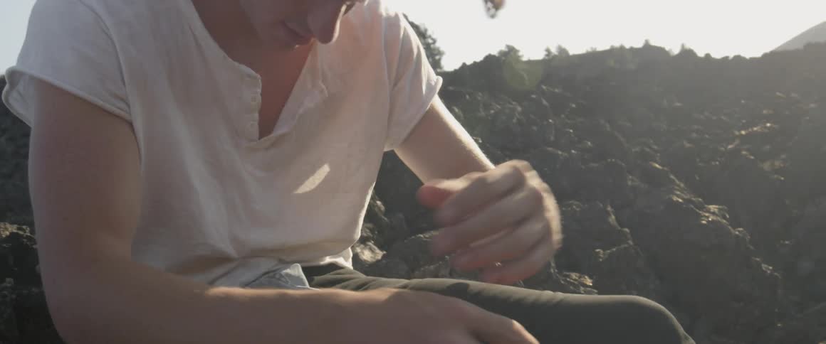 A man leans forward sitting on the rocks
