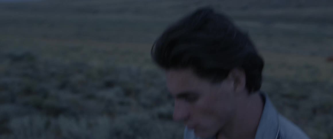 Man walks across a rural field at dusk