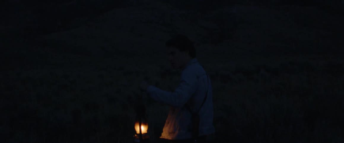 A man carries a glowing lantern in the dark
