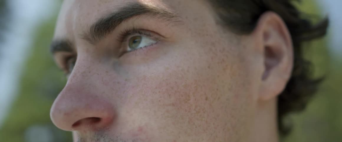 Man blinks and looks down on a sunny day
