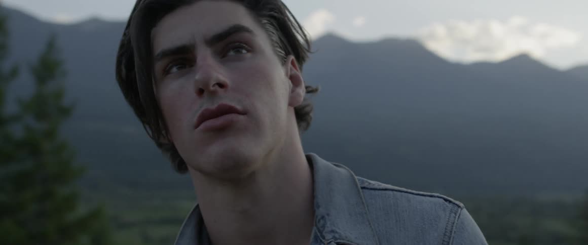 A man is looking up at the sky near the mountain
