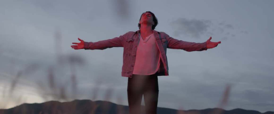 Man stretches out his arms as he stands outside