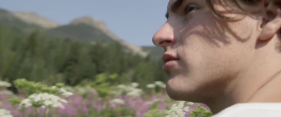 Man sits in a field of flowers as he looks around