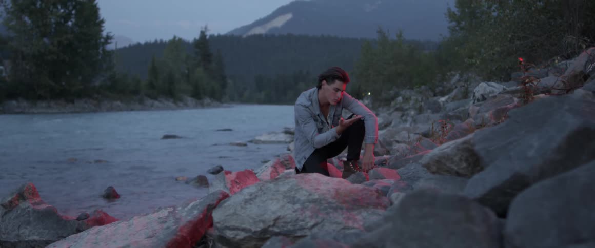 A man leans next to the river