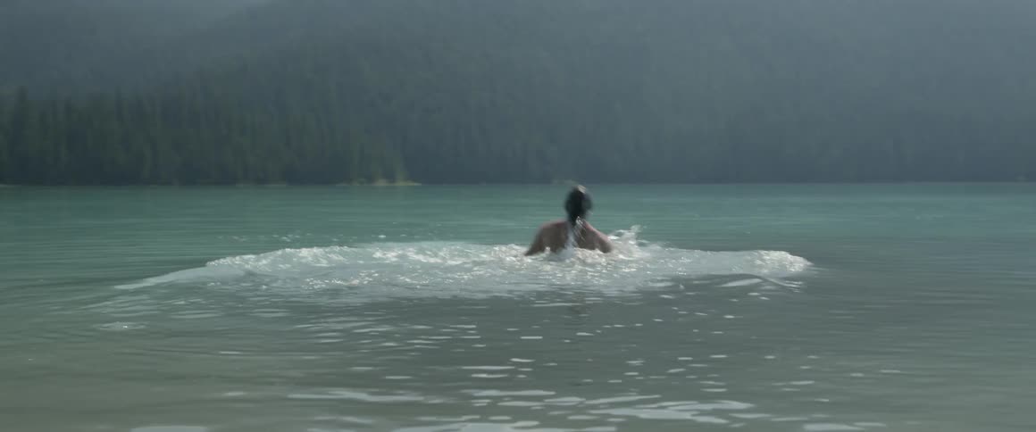 Man dives into lake and splashes the water on sunny day