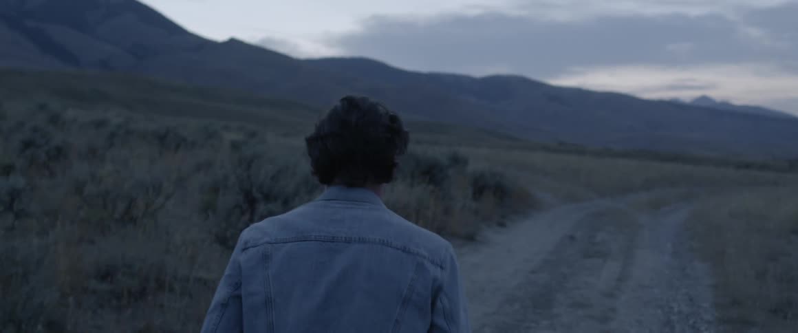 A man walks on a dirt road at dusk