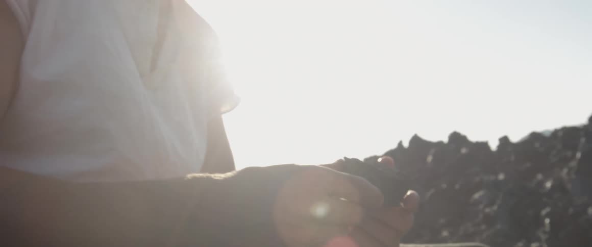 A man holds a rock and turns it over in his hands