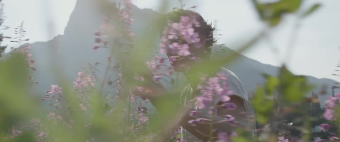 Man walks outside by bushes of lilacs