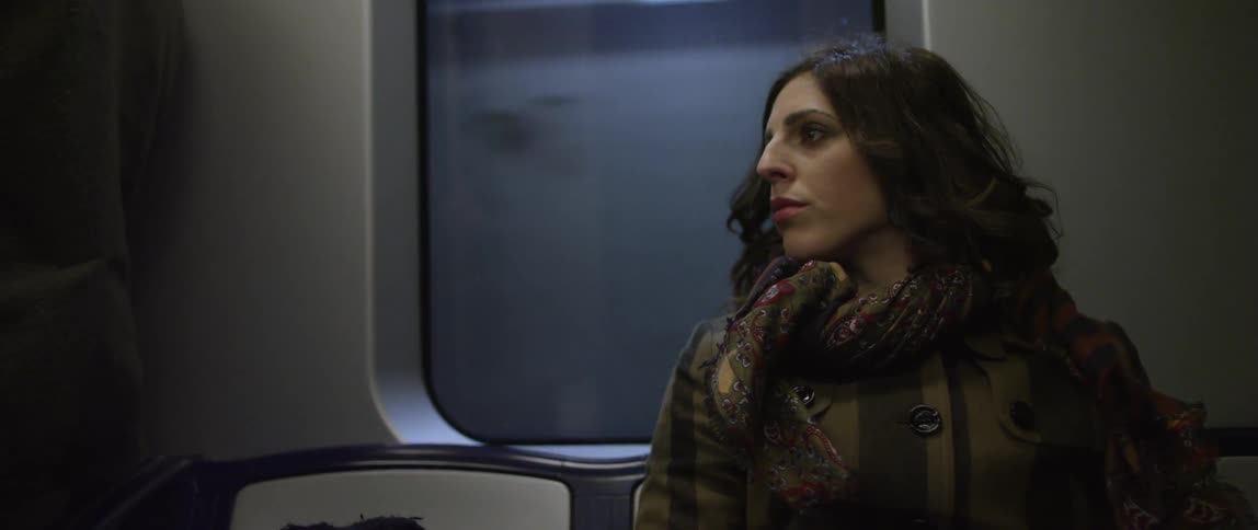 A brunette woman looking around as she travels on a subway train