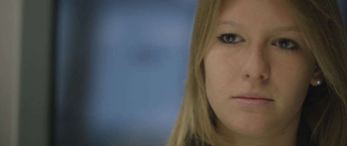 A young blonde woman stares off into the distance while riding on a metro