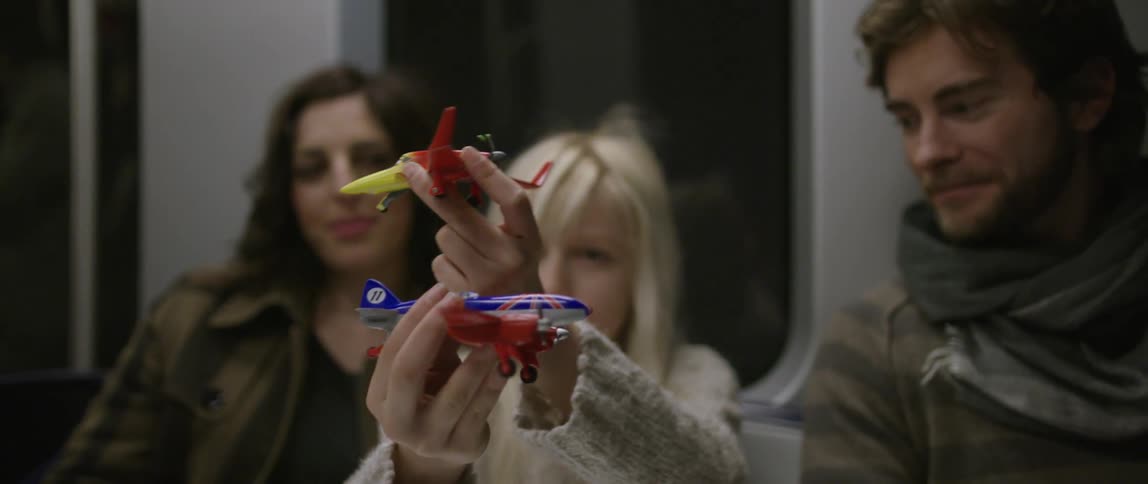 A girl plays with toy airplanes on the subway