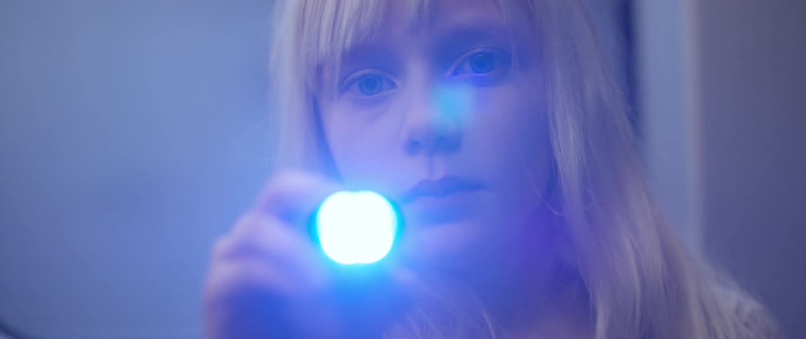 A young blond girl playing with a flashlight