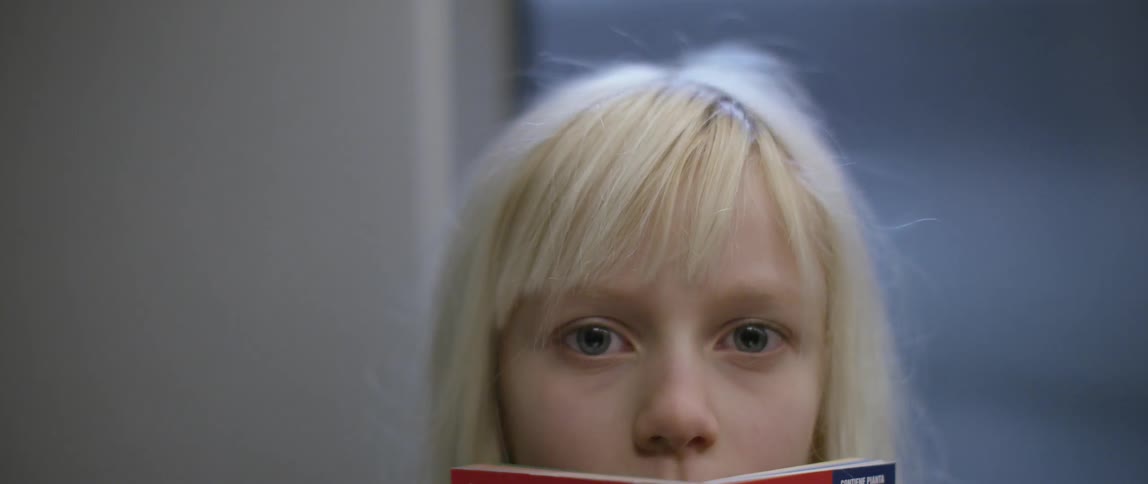 A blonde girl looks up from a book