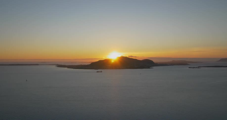The sun sets over a land mass in the ocean