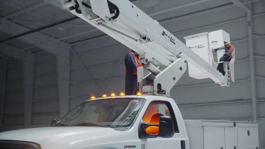 A man extends the lift on a utility truck