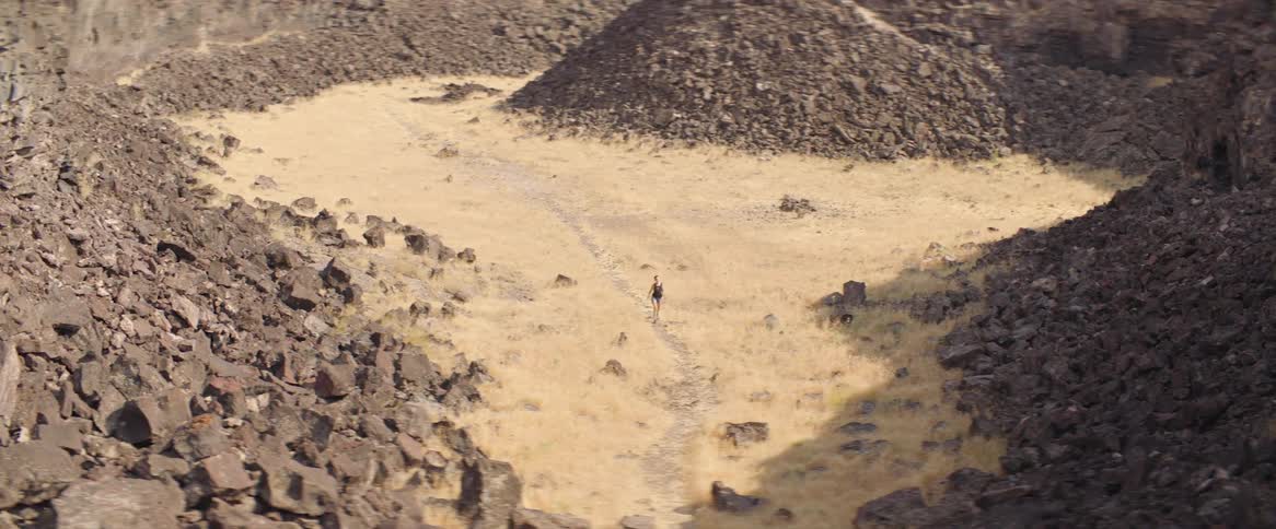 Person walks on a path through muddy rocky landscape