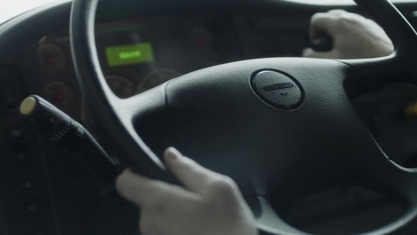 A person steers a truck steering wheel