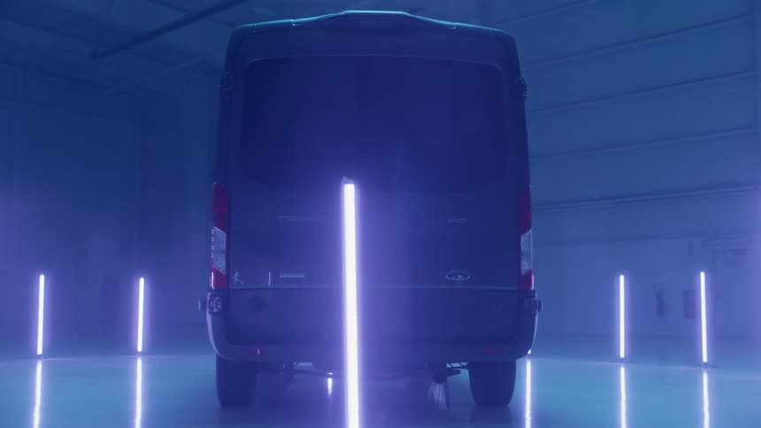 A van sitting in a hangar is surrounded by a circle of fluorescent lights