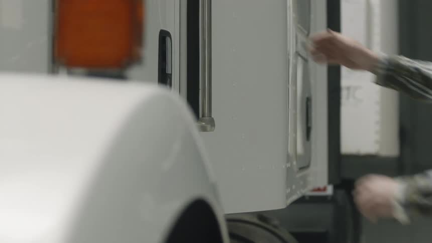 Man opens the door of a semi truck and climbs in