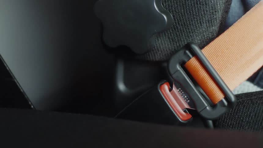 A person fastens their car seat belt