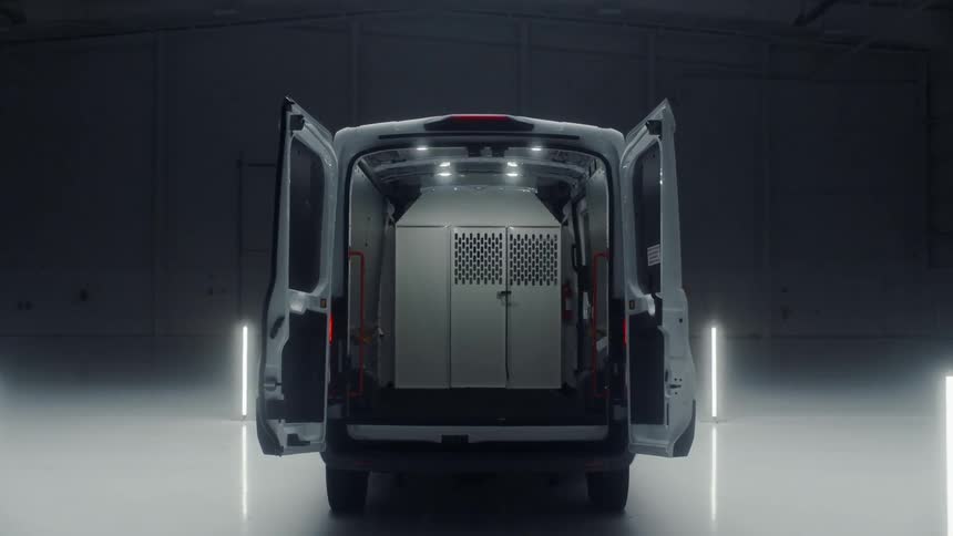 An empty van parked in a warehouse with doors open