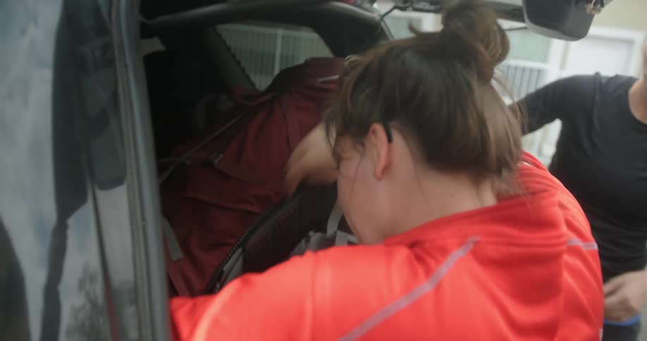 Man and woman put a large bag in the trunk of a vehicle