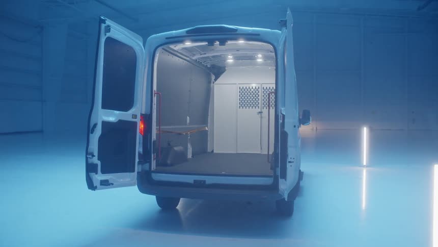 A van is sitting in a hangar with its doors open