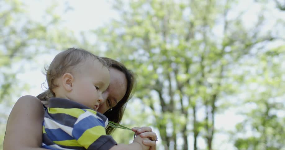 A woman hands grass to a young child she is holding