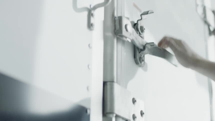 A man closes a truck door and latches it shut