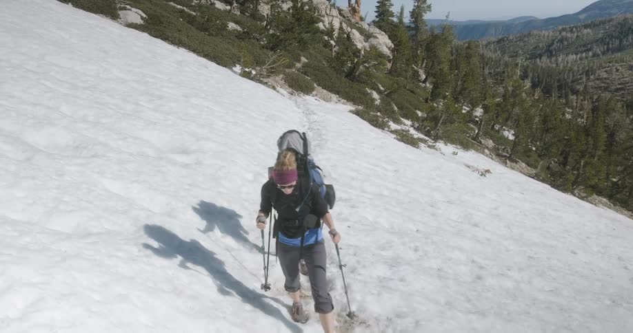 Hikers climb over snow in mountains