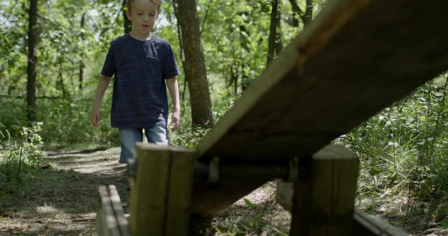 A young boy walks onto a seesaw